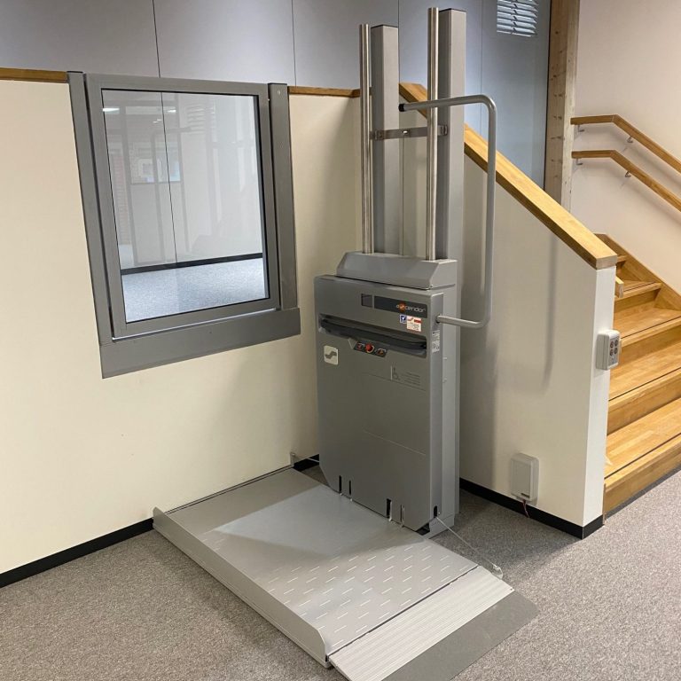 Treppenlift neben einer Wand, mit einer Plattform und zwei vertikalen Stangen in löhne Treppenlift neben einer Wand, mit einer Plattform und zwei vertikalen Stangen in löhne